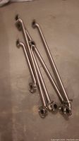 Four used stainless steel shower grab bars laid on a flat surface, visible mounting flanges at each end, varying lengths visible.