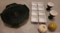 Overview of all items including black ceramic divided serving dish, six small white square dishes, two egg cup holders, and two salt and pepper shakers shaped as pumpkin and pine cone.