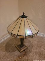 Full view of stained glass table lamp showing cream and beige geometric glass shade and brass base.