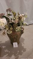 Large ceramic vase filled with artificial flowers seen from the front showing overall condition and style.