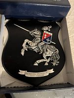 Close-up of the MCU plaque showing detailed knight on horse, emblem, and inscription with the plaque resting in the box
