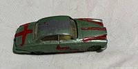 Top view of the green metal vintage toy car showing red paint markings and wear.