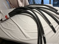 Multiple curved black foam tubing insulation pieces laid on a white surface.