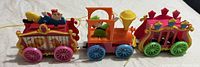 Photo showing three connected vintage plastic toy train carriages with colorful wheels and animal figures inside on each carriage.