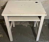 Front view of the vintage solid wood school house desk with white paint, showing scuffs and wear.