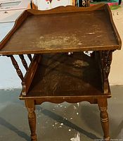 Photo showing the two-tier wooden side table with turned legs and surface wear.