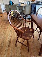 Single wooden armchair showing curved arms, spindle back, and contoured seat with visible wear.