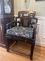 Front view of carved wood chair with decorative cushion