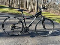 Full side profile of the black Specialized Ariel Sport bicycle outdoors on a paved driveway.
