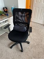 Full view of black adjustable swivel desk chair with mesh back, padded seat, and lumbar pillow placed on seat.