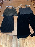 Two outfits laid flat on a wooden table showing pants paired with sleeveless tops: left outfit shows black silk tank with Talbots pinstriped pants, right outfit shows black beaded tank with Laura Ashley velvet pants.