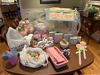 Full table view of all Easter and spring decor including figurines, eggs in bags, pastel buckets, Easter blocks, and a Spring is Here banner.