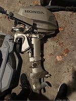 Full view of Honda outboard motor showing cover, lower unit, propeller and tiller handle