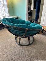 Side view of papasan chair showing dark brown rattan frame and teal cushion.