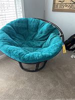 Full view of papasan chair showing large teal cushion and dark wooden frame in corner near window.