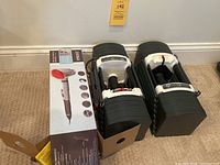 Two adjustable dumbbells on carpet beside boxed Homedics massager