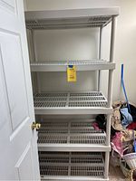 Full view of assembled rubbermaid style plastic storage shelf showing grid slatted shelves and overall construction.