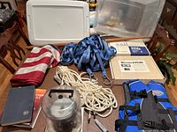 Full lot overview showing all items included: rope jacklines, life jacket, flag, log books, wooden handled item, sail track system, and clear storage bin.