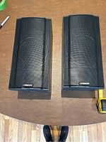 Top down view of two Klipsch speakers placed on a wooden surface showing front metal mesh grills and company logo.