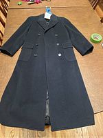 Full view of the navy wool coat laid flat showing double-breasted button front and two flap pockets.