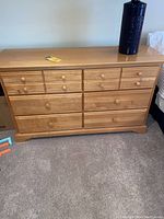 Front view of the light tone wood dresser showing 6 drawers and wooden knob handles.