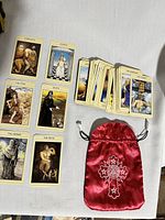 Full view of the complete spread with several tarot cards laid out including Strength, Justice, The Fool, Death, The Hermit, The Devil, and a stack of other cards with silk pouch visible.
