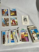 Full spread of cards with box and booklet on a white cloth surface