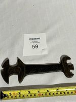 Antique cast iron multi wrench shown next to measuring tape indicating a length of approximately 6.5 inches.