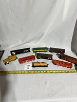 Wide shot of the 9 HO scale model train cars displayed with a measuring tape for scale, showing various colors and logos including CP Rail, CN, M&SL, and New York Central.