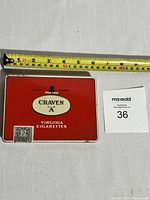 Rectangular Craven A Virginia Cigarettes tin with measuring tape to show size.