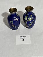 Pair of small blue cloisonné vases on white fabric with a MaxSold lot card in front.