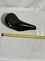 Full side view of the black leather bicycle saddle showing length measurement approximately 11 inches.