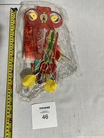 Photo of a colorful vintage traditional Chinese kite wrapped in plastic, showing detailed silk wing design and wooden spars with string tied around.