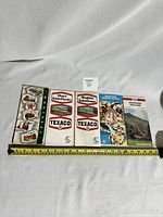 Top view of all five road maps spread out to show covers and sizes with measuring tape for scale.