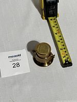 Top-down and angled view of the solid brass mortar showing size against measuring tape and details of the handles and interior.