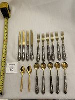 Overview photo of the 15 piece flatware set arranged on a table with measuring tape to show size.