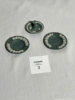 Three-piece set including a ring holder and two plates, displayed on a fabric background.
