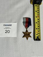World War II 1939-1945 Star Medal with ribbon and measuring tape for scale, approximately 5.7 cm in height
