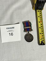 Full view of the WWII Canada Voluntary Service Medal with measuring tape for size reference showing the medal approximately 6 cm long including ribbon.