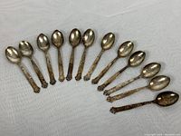 Twelve antique 800 silver espresso spoons arranged in a fan shape showing overall set and condition