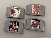 Four Nintendo 64 game cartridges including Madden Football 64, Kobe Bryant in NBA Courtside, WWF War Zone and Wayne Gretzky's 3D Hockey showing front labels