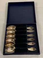 Original dark blue box with black velvet dividers holding six sterling silver coffee spoons vertically arranged.