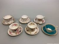 Front view showing all six teacups and saucers with varied floral patterns and one turquoise set.