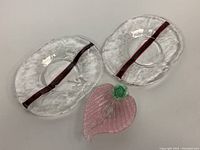 Top view of two clear texturized glass Murano serving plates with red stripe and pink textured leaf bowl with green stem detail