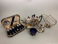 Full lot view showing tea/coffee set, candleholders, basket, cobalt bowl, and spoon set in original box