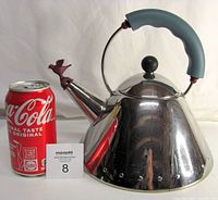 Kettle shown next to a soda can for size reference, displays polished steel surface and blue handle.