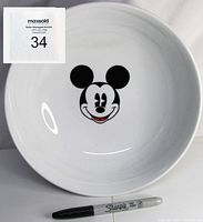 Top-down view of white ceramic serving bowl with centered black and white Mickey Mouse face with red tongue on inside bottom, Sharpie marker provided for scale