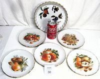 Photo showing one 9 inch Evesham quiche or pie dish and five 7 3/8 inch dessert plates with painted fruit designs and gold trim, along with a soda can for size reference.