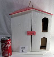 Closed view of the white and pink wooden doll house with Coca-Cola can for size reference.
