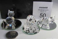 Front and slightly angled view of all three Swarovski crystal figurines (cat, puppy, bunny) on round mirror bases next to a quarter for scale, showing clear faceted crystal work and minor damage on ears.